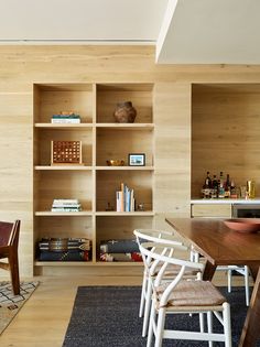 a dining room table with chairs and bookshelves in the back ground, next to an open bookcase