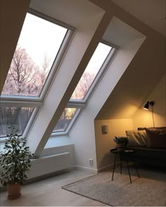 an attic bedroom with three large windows and a couch in the corner next to it