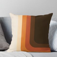 an orange and brown throw pillow sitting on top of a couch