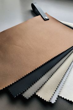 four different colors of fabric on a table with a black object in the middle one