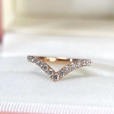 a diamond ring sitting on top of a white cloth covered box with its lid open