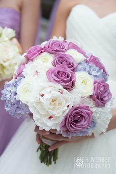 a bride holding a bouquet of purple and white flowers