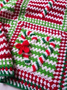 a crocheted blanket with red, green and white designs on it sitting on top of a table