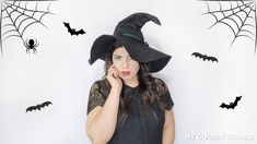 a woman wearing a witches hat and holding her hand to her face while looking at the camera