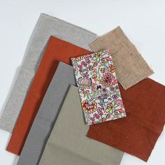 four different colors of fabric laid out on top of each other, including red, grey, and orange