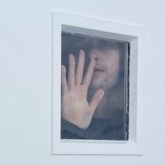 a man holding his hand up to the window