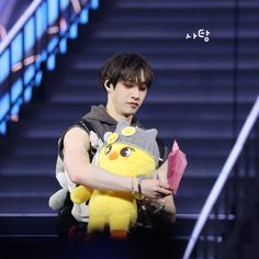 a young man holding a stuffed animal on top of a set of stairs in front of him