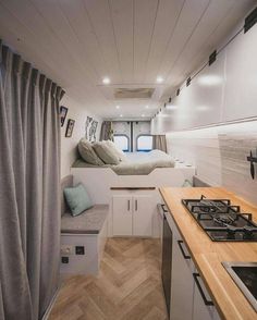 the interior of a camper with a bed and kitchen