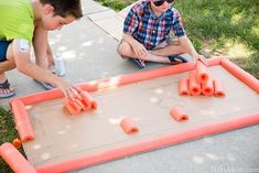 two boys playing with an inflatable board game on the sidewalk while another boy watches