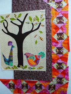 a quilted tree with birds on it and an orange, pink, green, purple, and white background