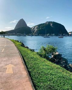 there is a bike path on the side of the water with mountains in the background