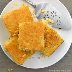 three pieces of cornbread on a white plate with a spatula next to it