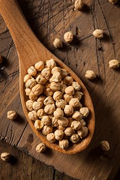 a wooden spoon filled with nuts on top of a table