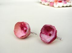 two small pink flowers sitting on top of a table