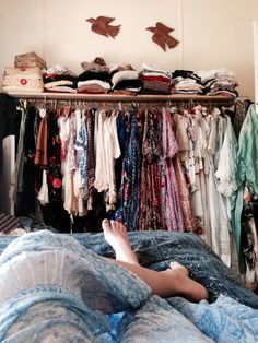 a person laying on a bed in front of a closet full of clothes