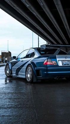 a blue sports car parked under an overpass