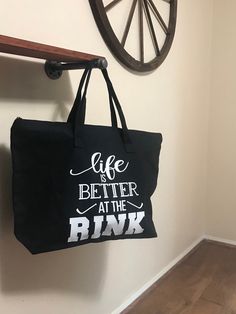 a black tote bag hanging on the wall next to a wooden shelf and clock