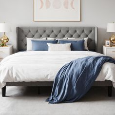 a bed with blue and white comforters in a bedroom next to two nightstands