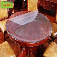 a round wooden table with chairs around it and a clear plastic cover over the top