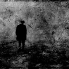 a black and white photo of a person standing in front of a wall