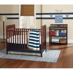 a baby crib with blue and white striped bedding in a nursery room setting