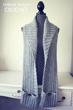 a knitted vest sitting on top of a white dresser next to a black and white polka dot tie