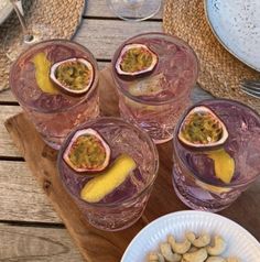 three glasses filled with different types of food on top of a wooden table next to plates and utensils