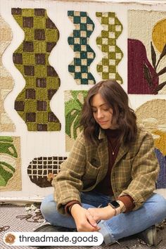 a woman sitting on the ground in front of a quilt