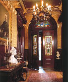 an ornate entry way with chandeliers and paintings on the walls, along with a statue