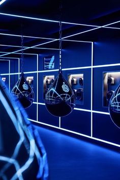 several boxing gloves hanging from the ceiling in a room with blue walls and black lighting