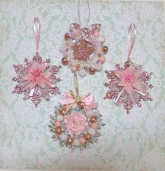 three ornaments hanging on a wall with pink flowers and pearls in the shape of snowflakes