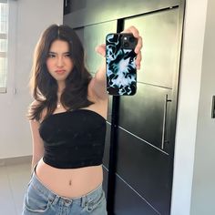 a young woman taking a selfie with her cell phone in front of a refrigerator