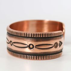 two different types of copper rings on a white surface, one with an intricate design