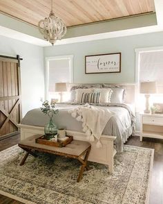 a bedroom with a bed, dresser and table in front of a barn style door