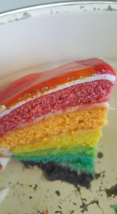 a slice of rainbow cake sitting on top of a white plate