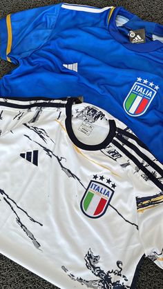 three soccer jerseys laying on the ground next to each other, all different colors and sizes