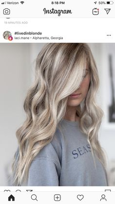 a woman with long blonde hair is looking at her cell phone while wearing a sweatshirt