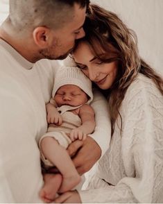 a man and woman holding a baby in their arms