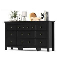 a black dresser with many drawers and pictures on it's top shelf in front of a white background