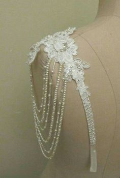 a white headpiece with pearls and flowers on it's side, sitting on a mannequin