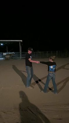 two people standing in the sand with their arms extended and one person holding out his hand