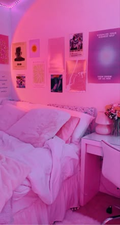 a bedroom with pink walls and pictures on the wall above the bed, along with a desk