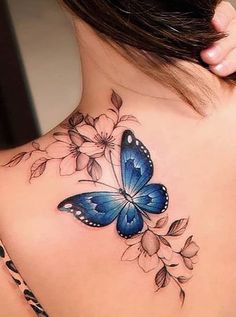 a woman with a blue butterfly tattoo on her upper back shoulder and flowers around the neck