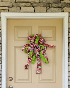 a red and green bow on the front door of a house that is decorated for christmas