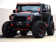 a black jeep with red leds parked in front of a white wall and building