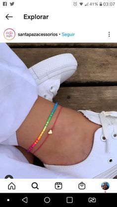 a woman's foot wearing white sneakers and colorful bracelets