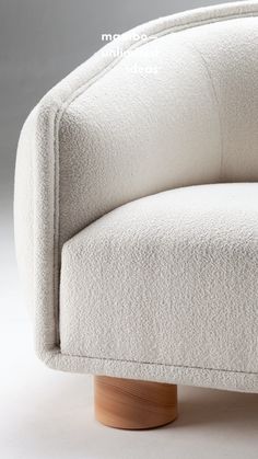 a white chair with wooden legs and an upholstered cushion on the back side