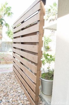 a wooden fence is shown in front of a house with gravel and rocks on the ground