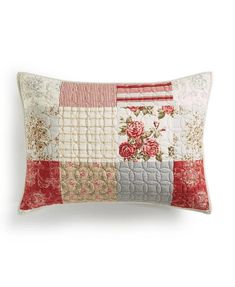 a white pillow with red and pink flowers on the front, sitting on a white surface