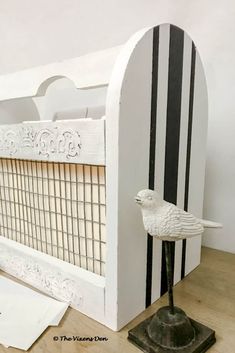 a white bird statue sitting on top of a wooden table next to a piece of paper